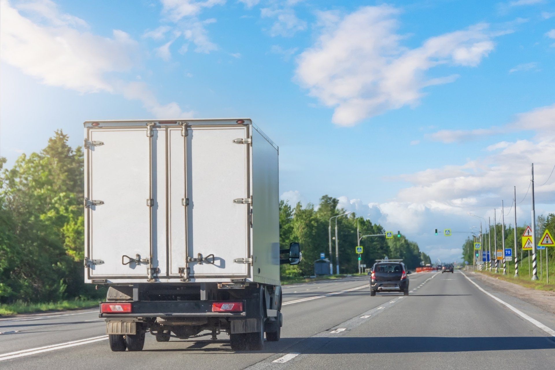Un camion blanc roule sur une autoroute à côté d'une voiture.