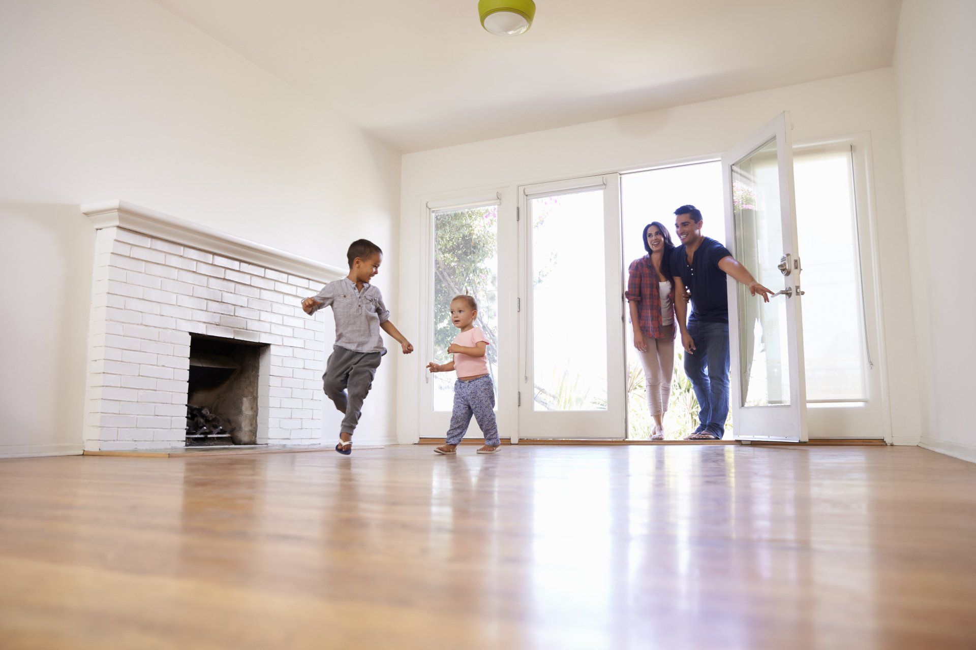 Une famille se tient dans un salon vide dans leur nouvelle maison.