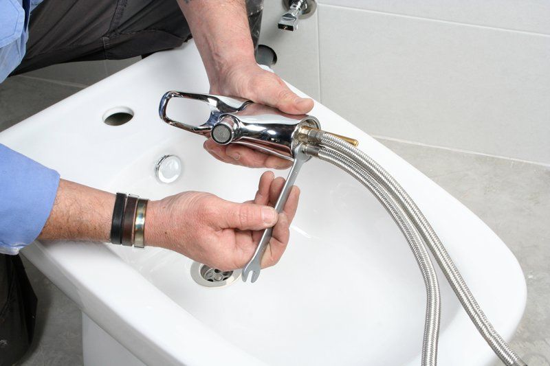 Plumber Installing Faucet On Bidet In Bathroom — KNP Plumbing and Gas — Airlie Beach, QLD