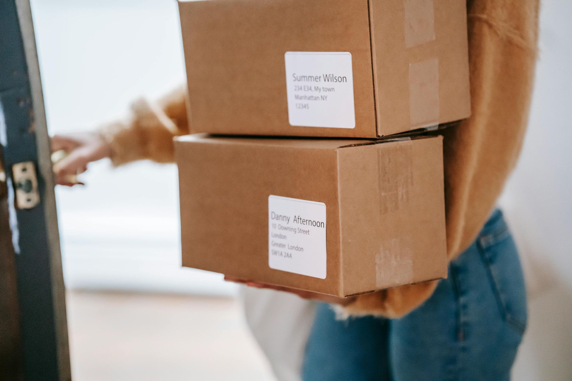 A woman is holding a stack of cardboard boxes in her hands.
