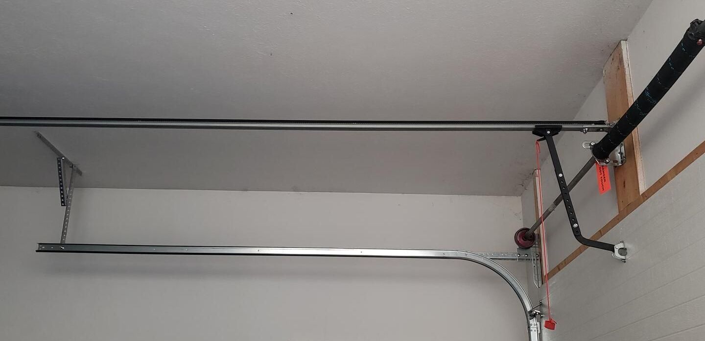 Newly installed garage door torsion spring system with metal tracks and ceiling mount, showcasing safe and professional garage door setup for residential use.
