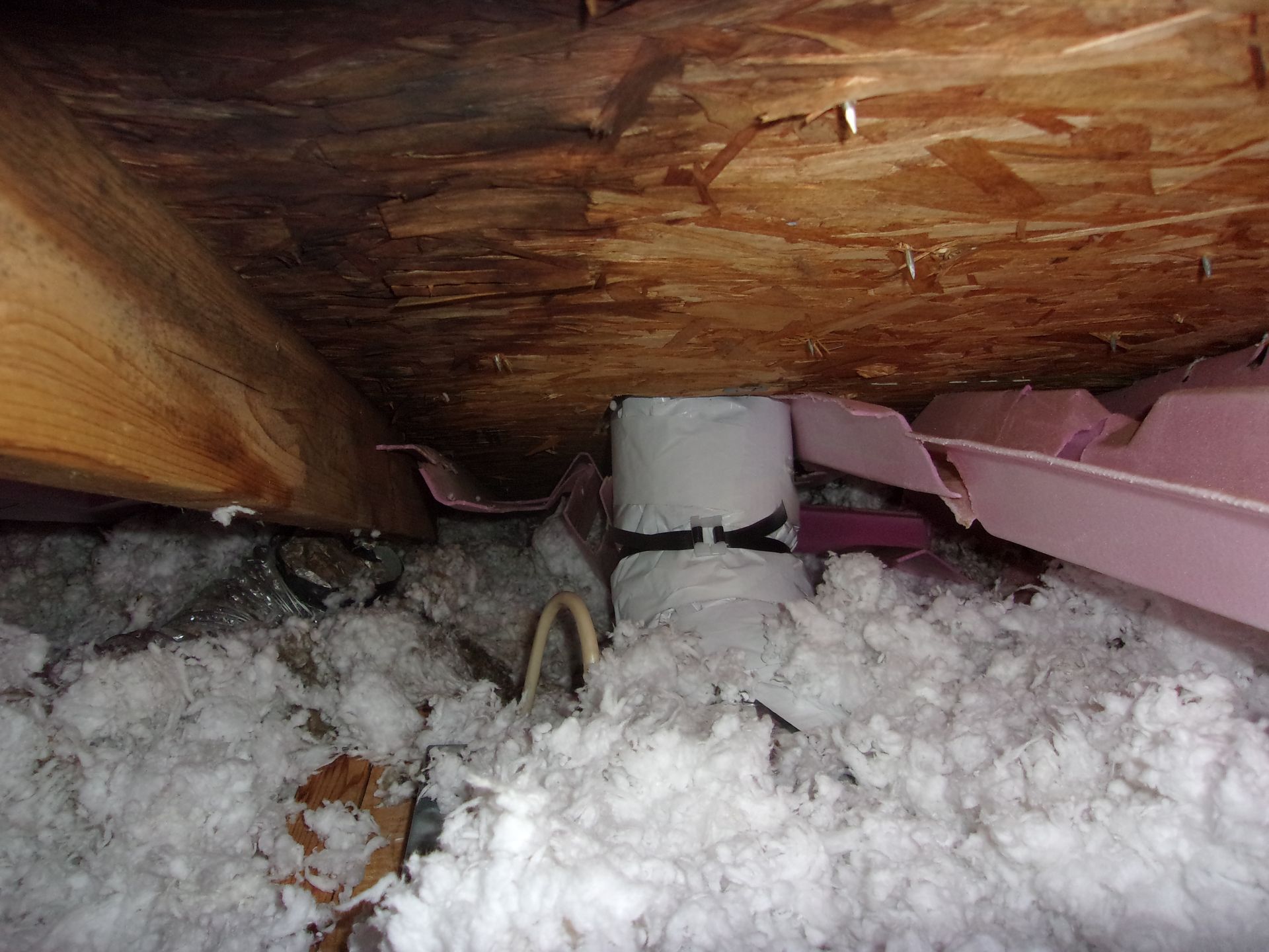 Uneven insulation in an attic and foam insulation falling away from the roof