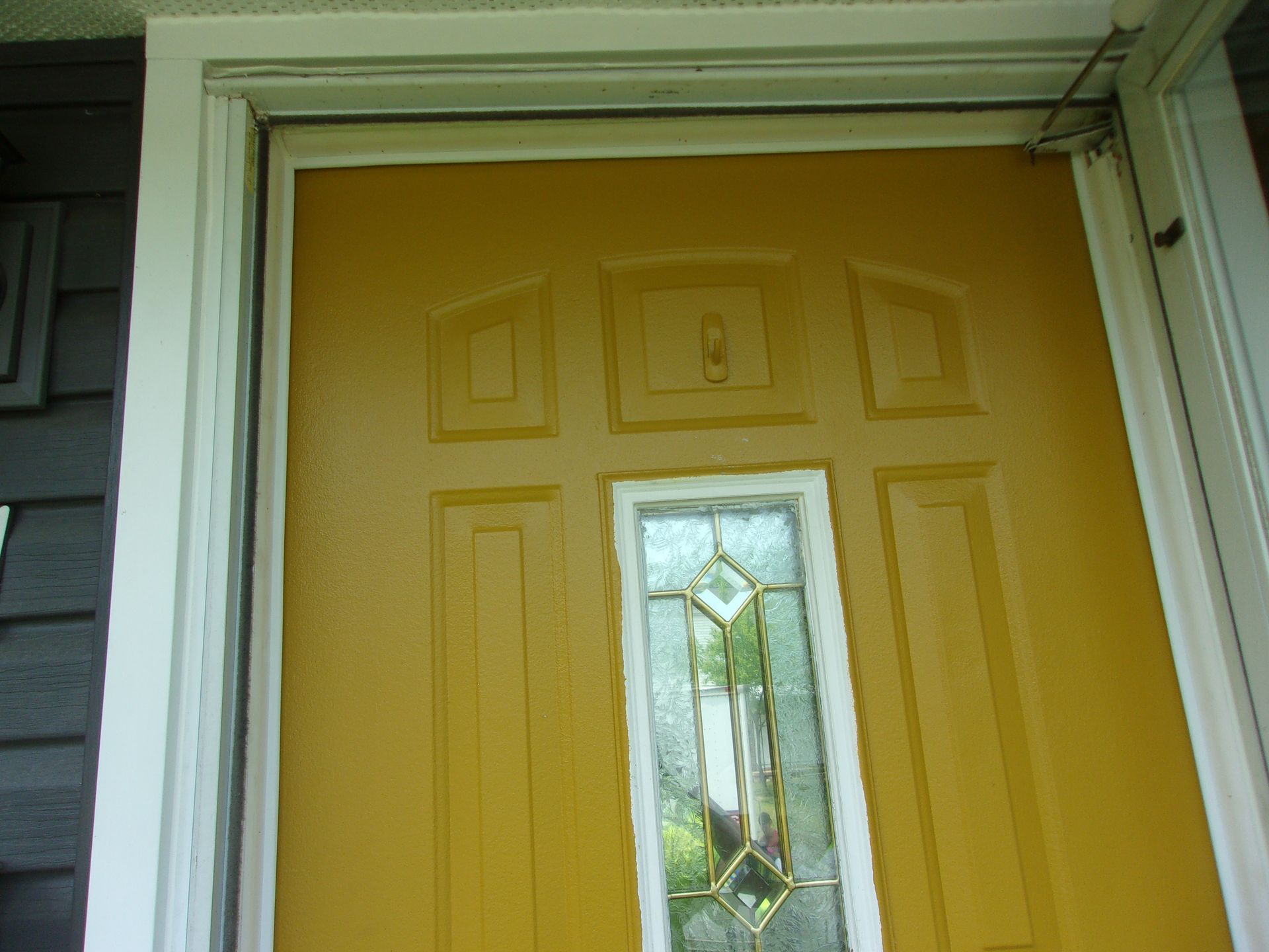 Yellow front door with a stained glass window and white trim.