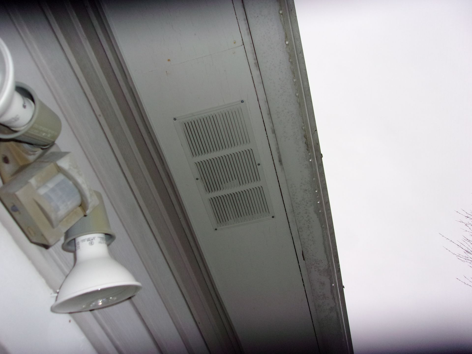 White soffit with three rectangular vents and a security light fixture. The soffit is near a roof's edge.