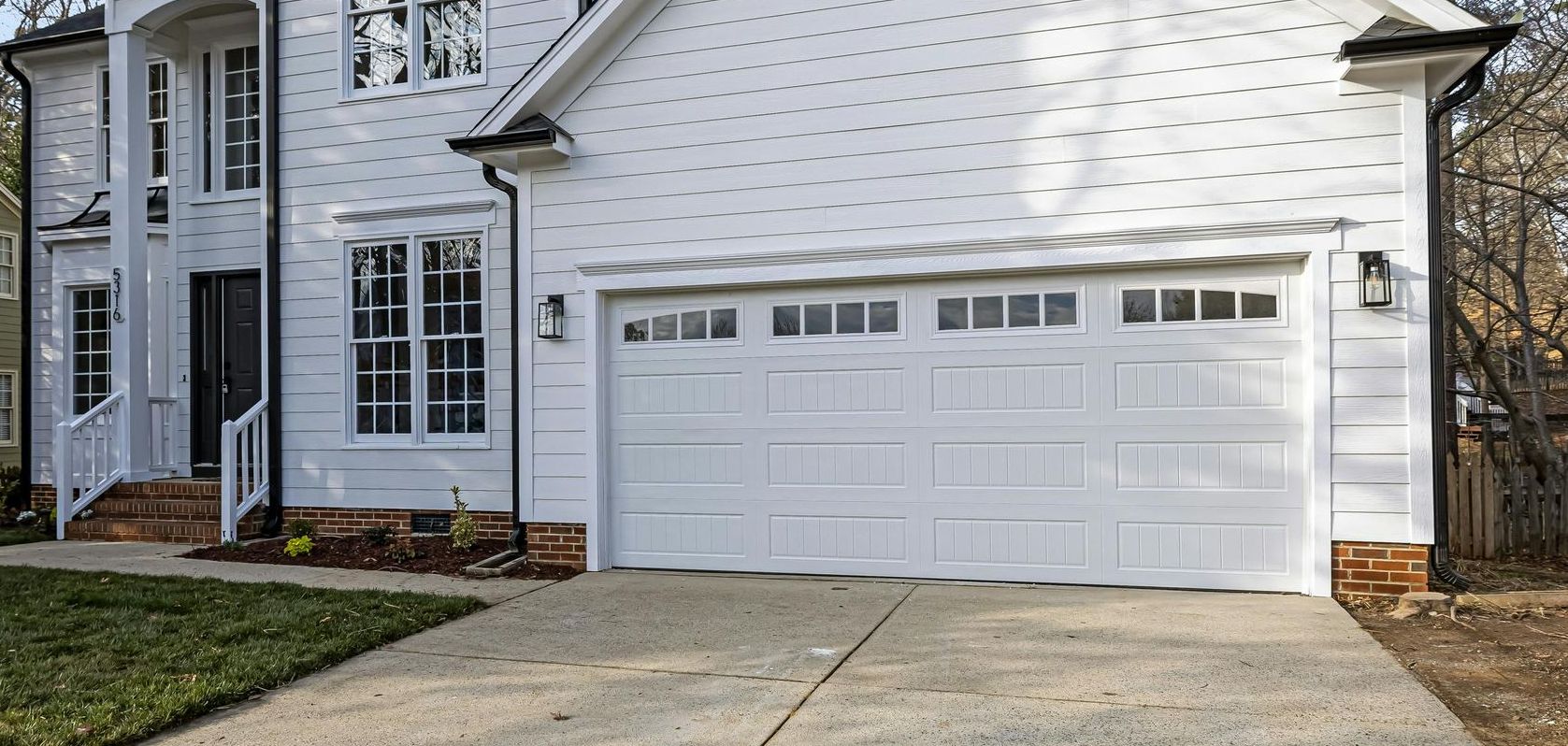 A white house with a white garage door and a driveway.