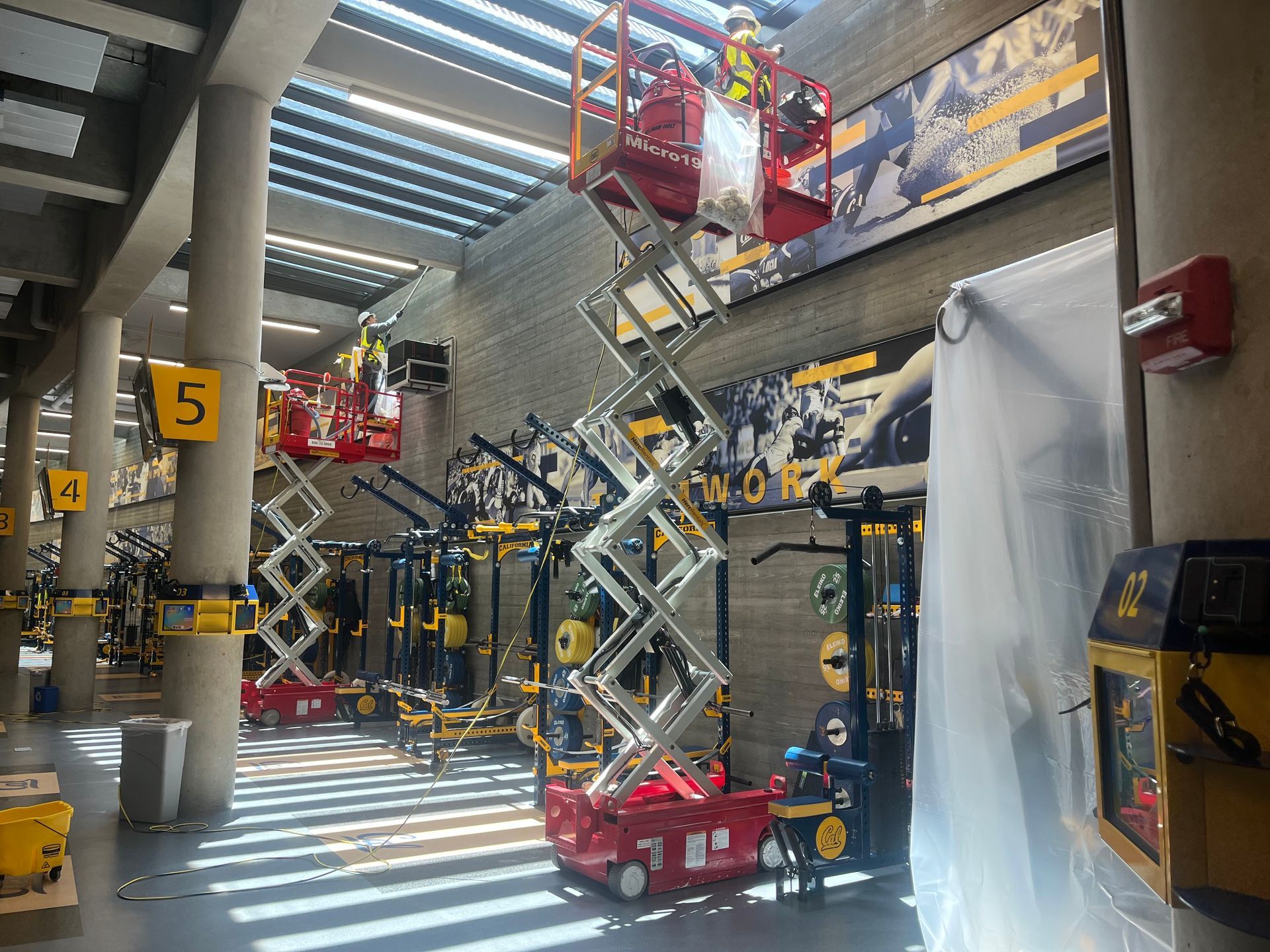 A man is standing on a scissor lift in a building.