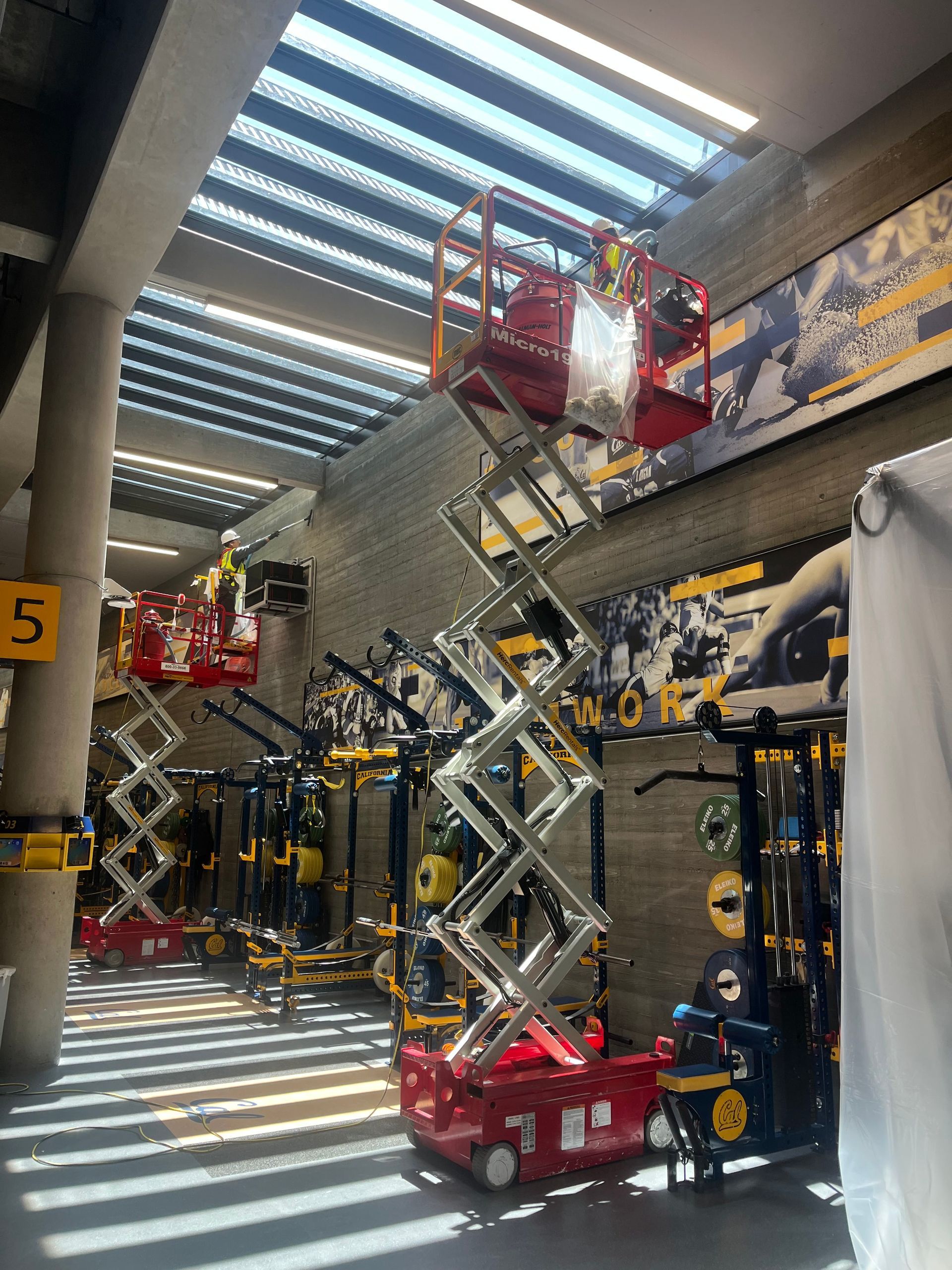 A group of scissor lifts are sitting in a gym.