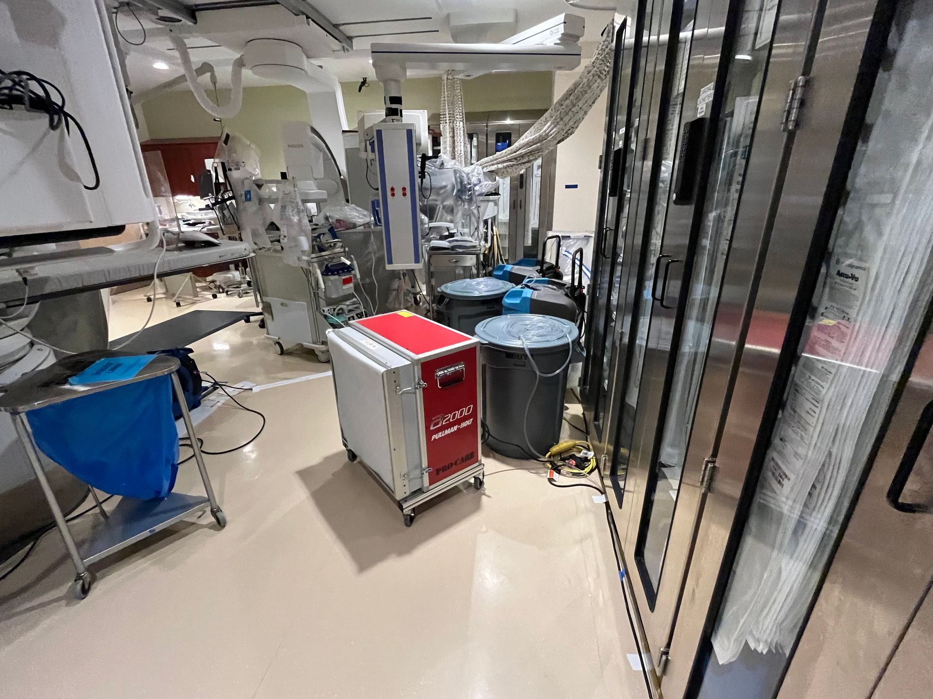 A room in a hospital with a lot of equipment and trash cans.