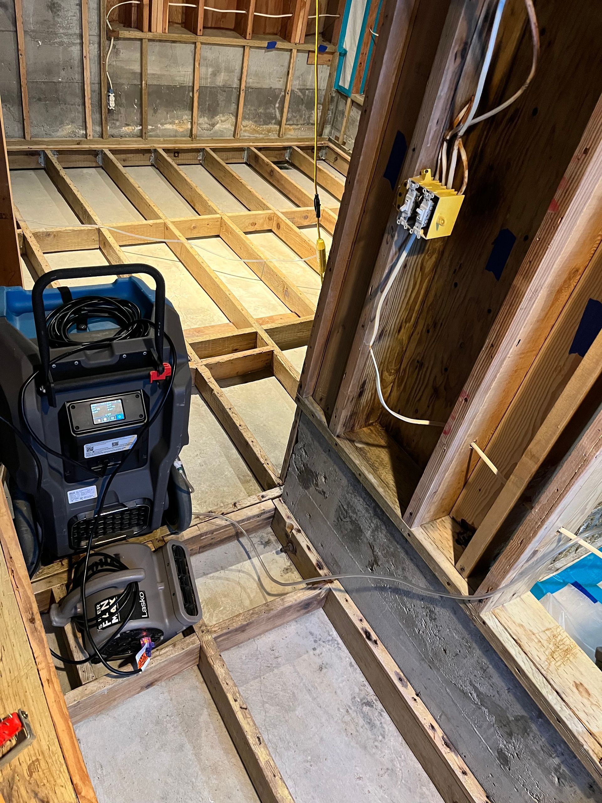 A vacuum cleaner is sitting on the floor of a room under construction.