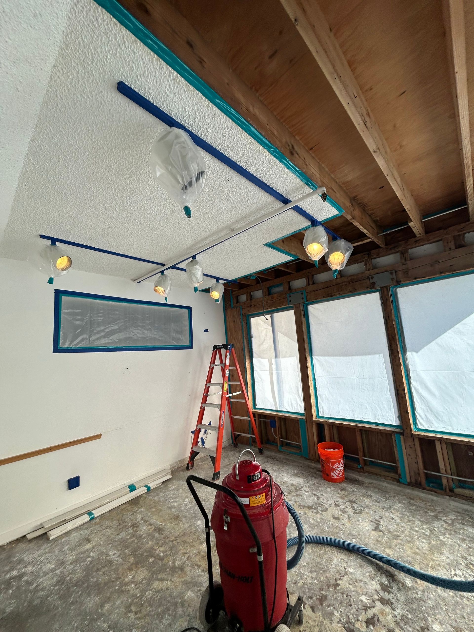 A room with a vacuum cleaner and a ladder in it.