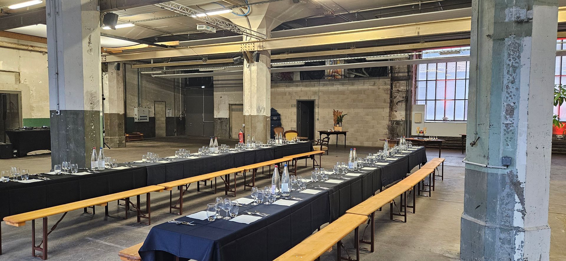Une grande salle avec des tables et des bancs installés pour une fête.