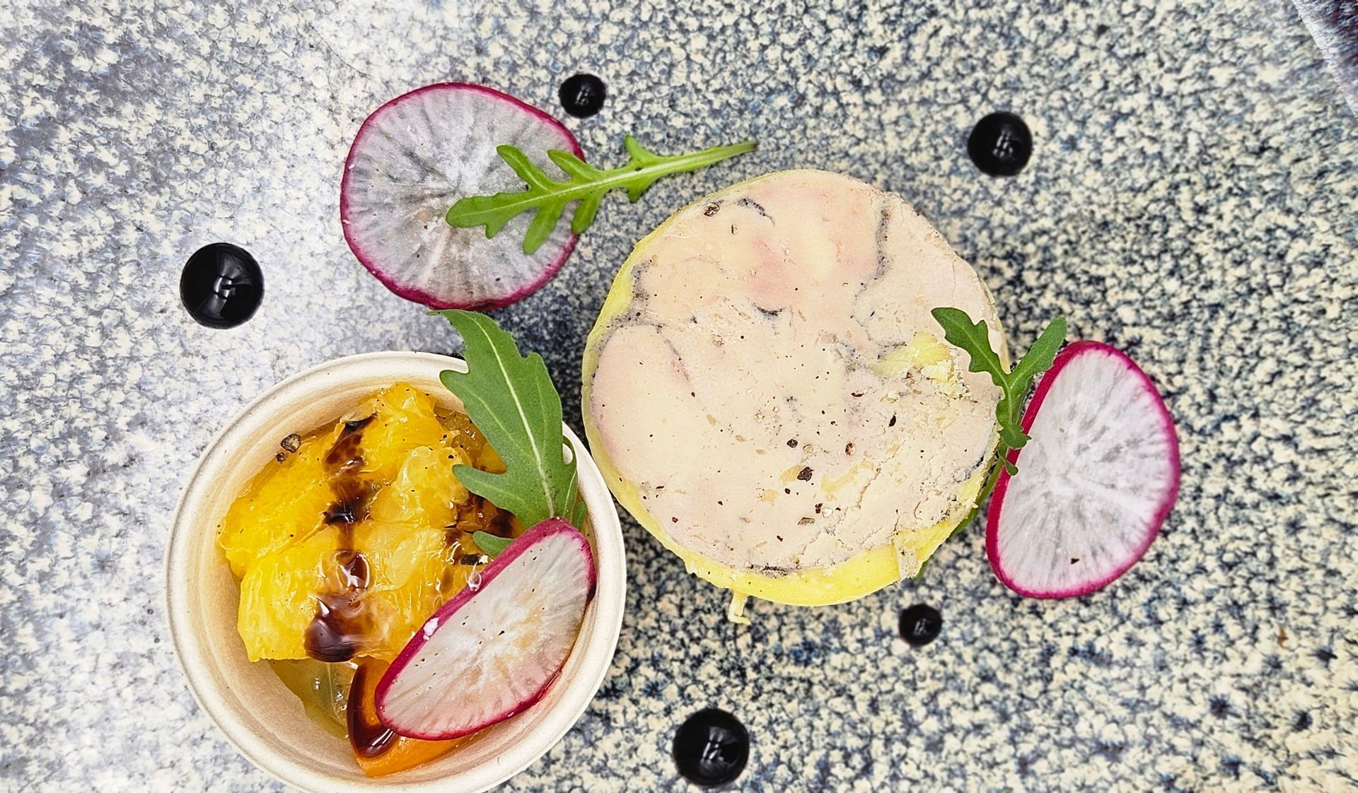 Une assiette de nourriture avec des radis et un bol de fruits sur une table.