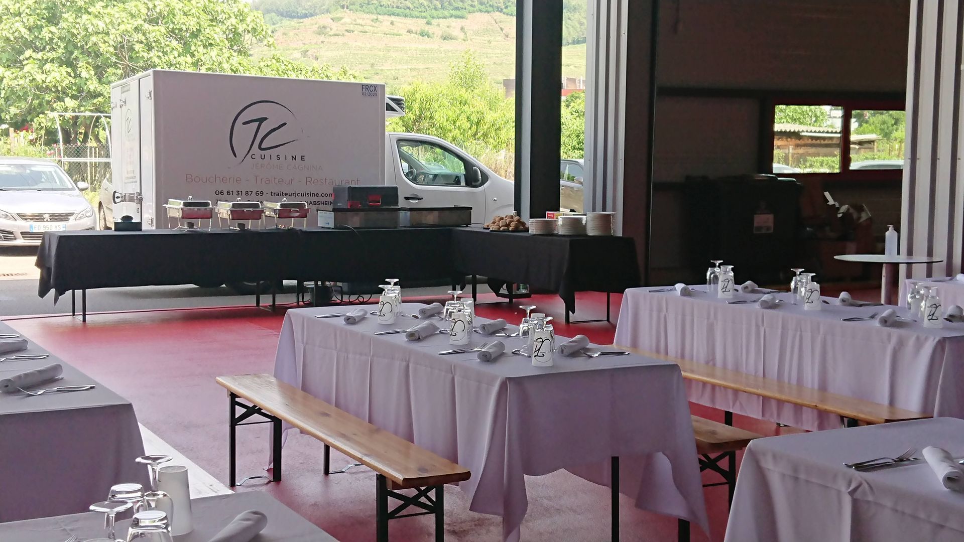Une grande salle avec des tables et des bancs et un camion en arrière-plan