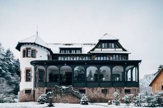 Une grande maison avec beaucoup de fenêtres est recouverte de neige.