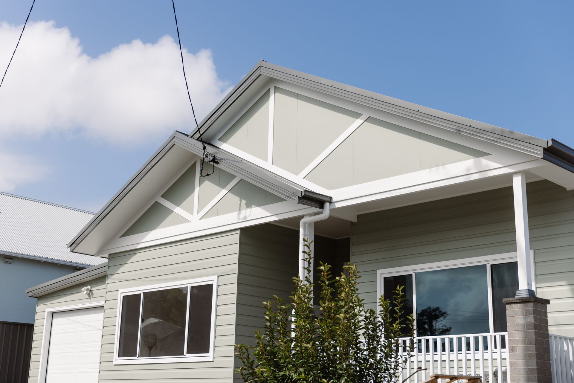 Open-plan living space with a light green sofa and kitchen cabinets, wooden flooring, and a dining table with chairs.