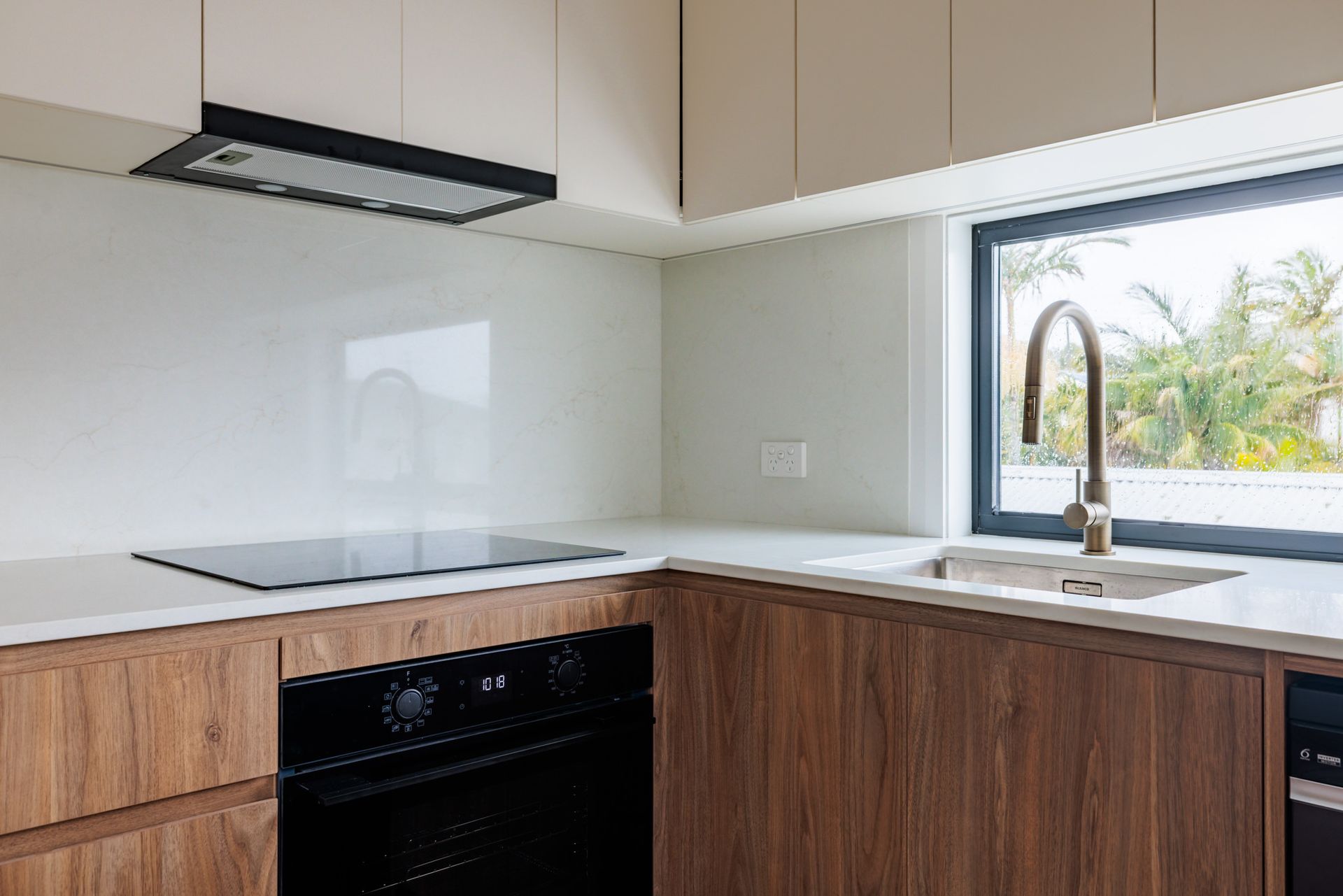 

Modern kitchen in granny flat build at Brown Street Redhead with white cabinetry and engineered stone benchtop
