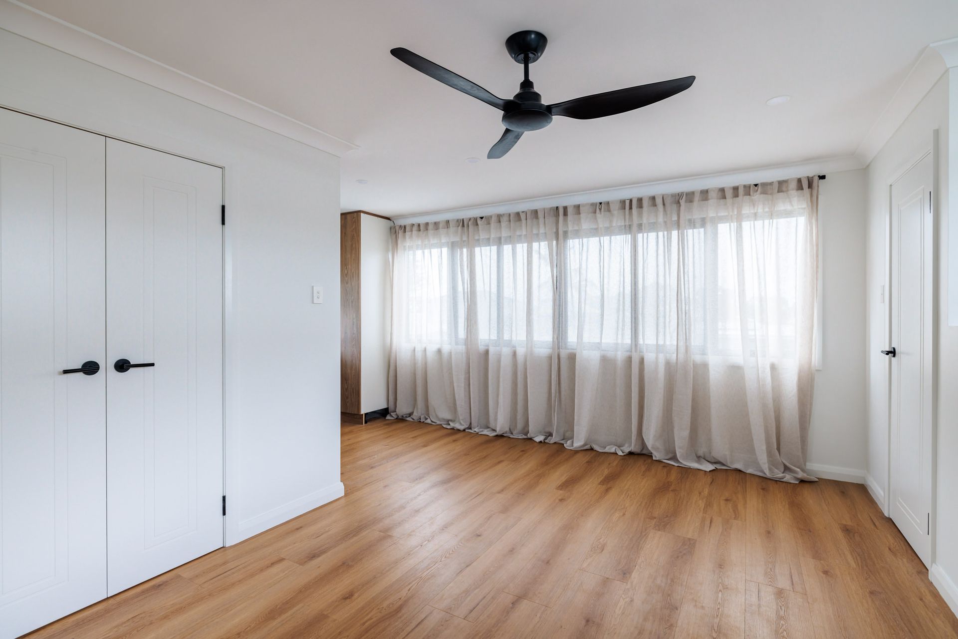 Open plan living area with sheer curtains in self-contained granny flat, Brown Street Redhead, neutral modern interior