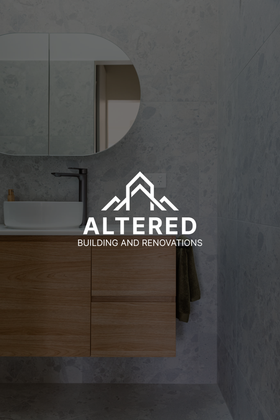 A smiling construction worker wearing a black polo shirt, tool belt, and cap, standing in a partially framed building.