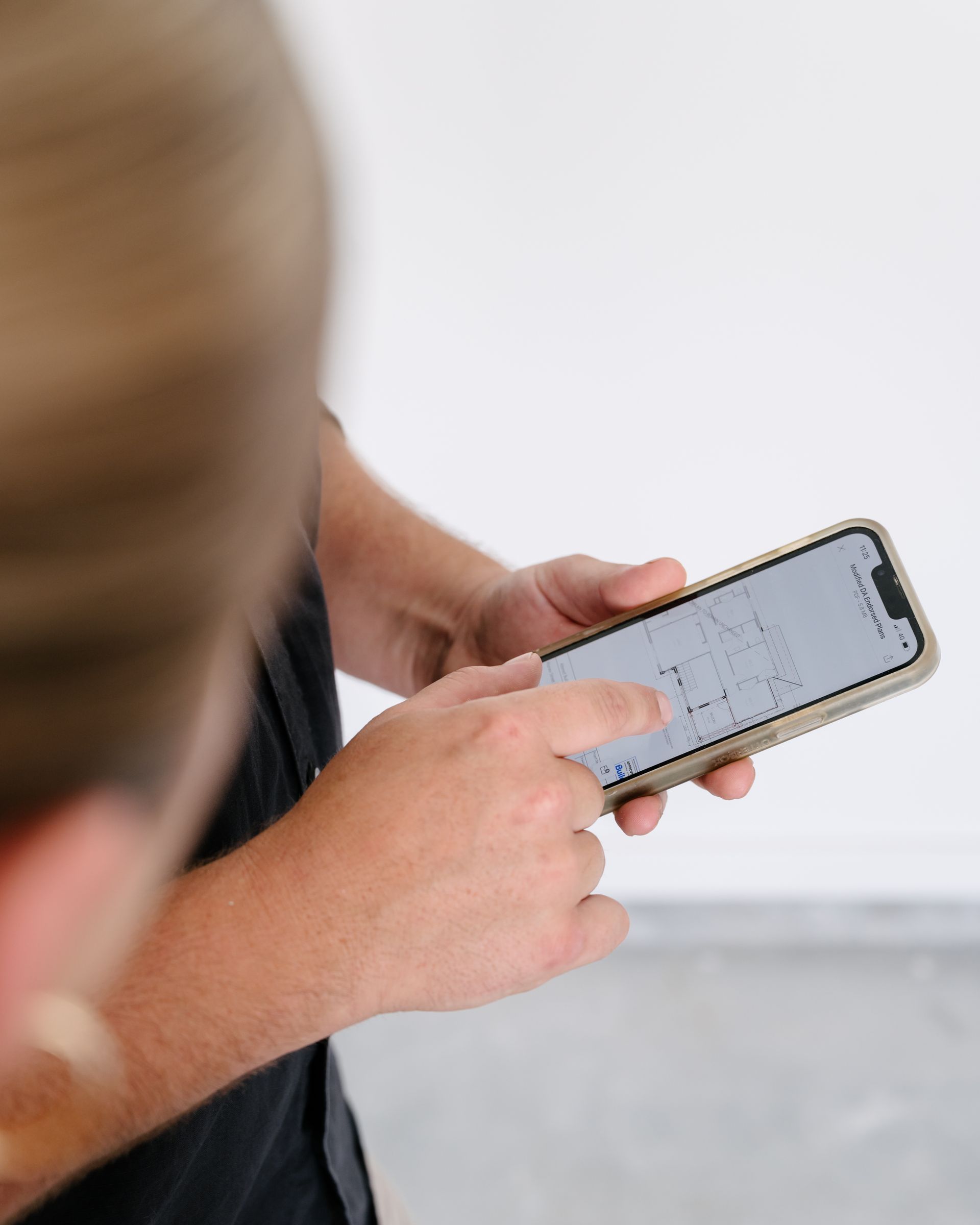 A person wearing a black shirt looks at a building floor plan displayed on their smartphone.
