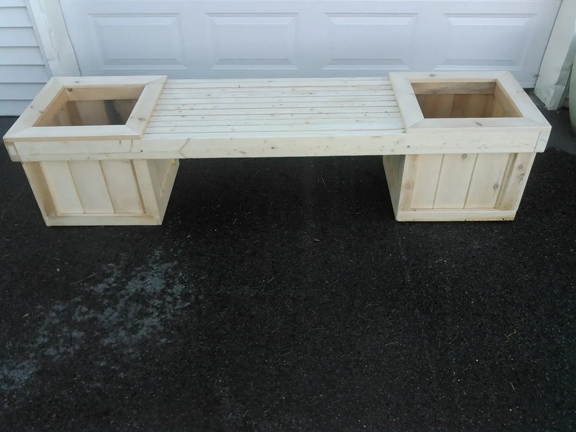 Wooden bench with built-in planters, painted white, placed outside against a garage door.