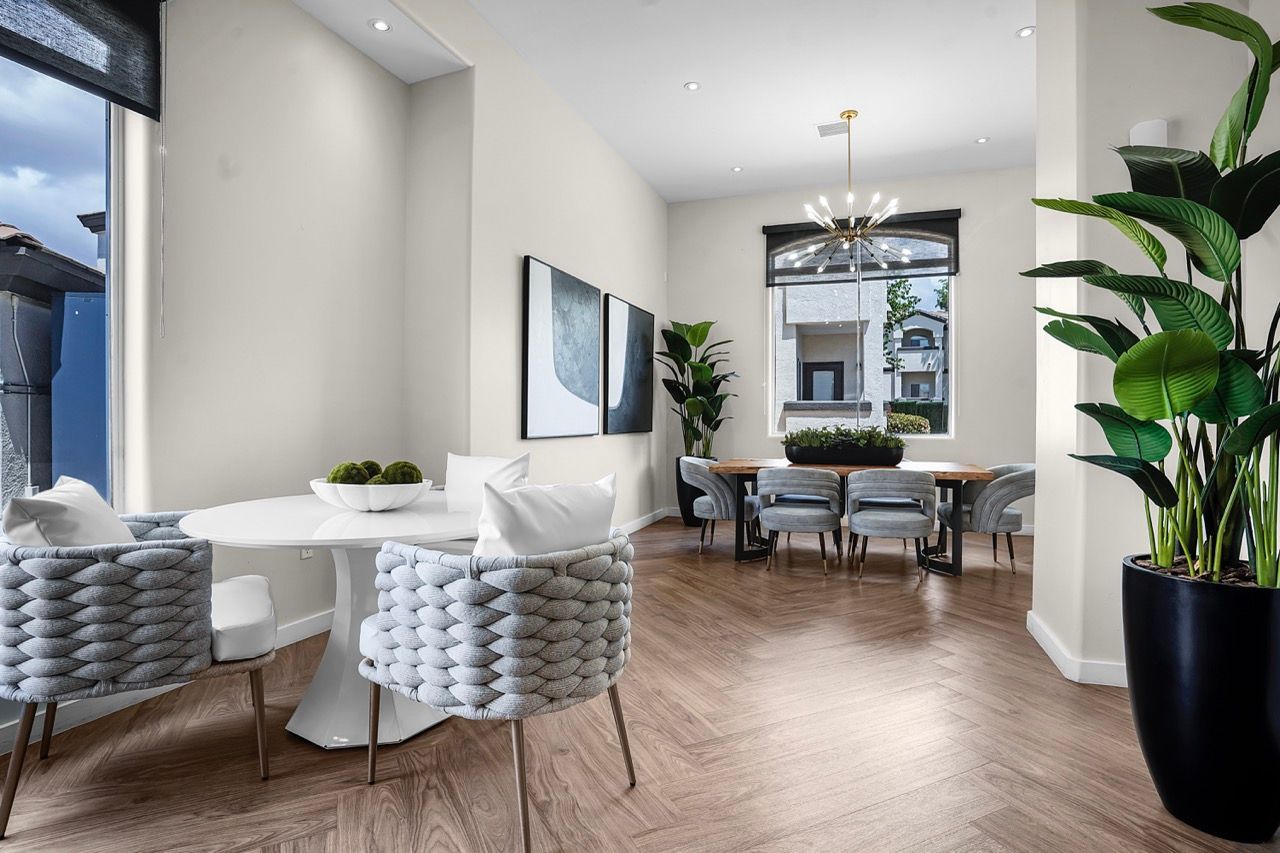 Bright modern community lounge with a round white table, woven chairs, and potted plants at Broadstone Heights in Albuquerque, NM.