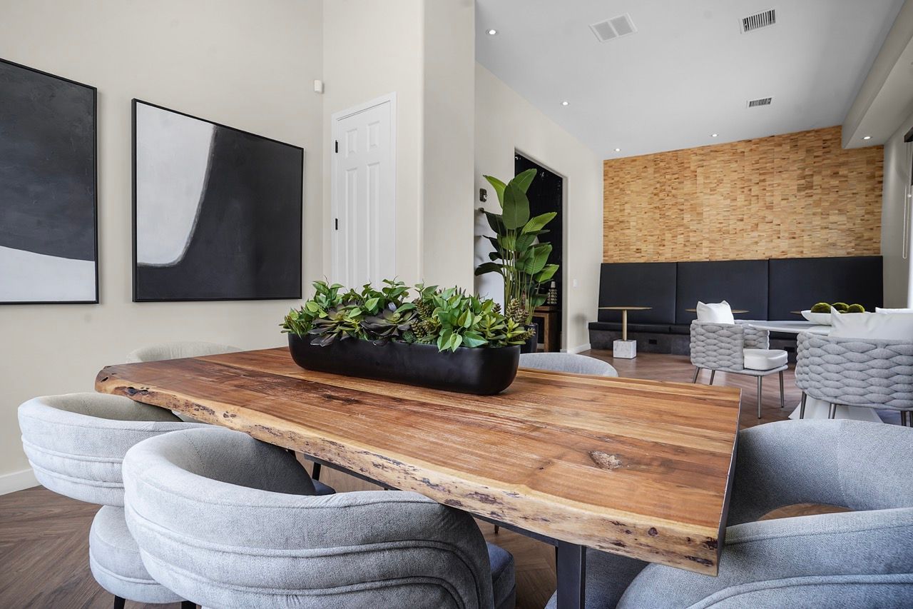 Interior community lounge with a large live-edge wooden table, planters, and comfortable grey chairs at Broadstone Heights in Albuquerque, NM.
