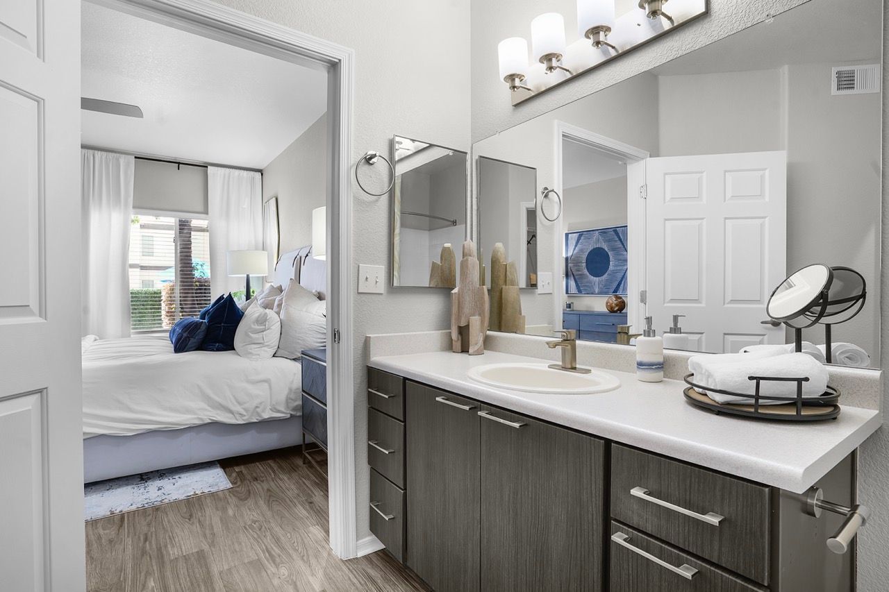 Bathroom vanity with double sink, mirrors, and towels; doorway to a bedroom at Broadstone Heights in Albuquerque, NM.