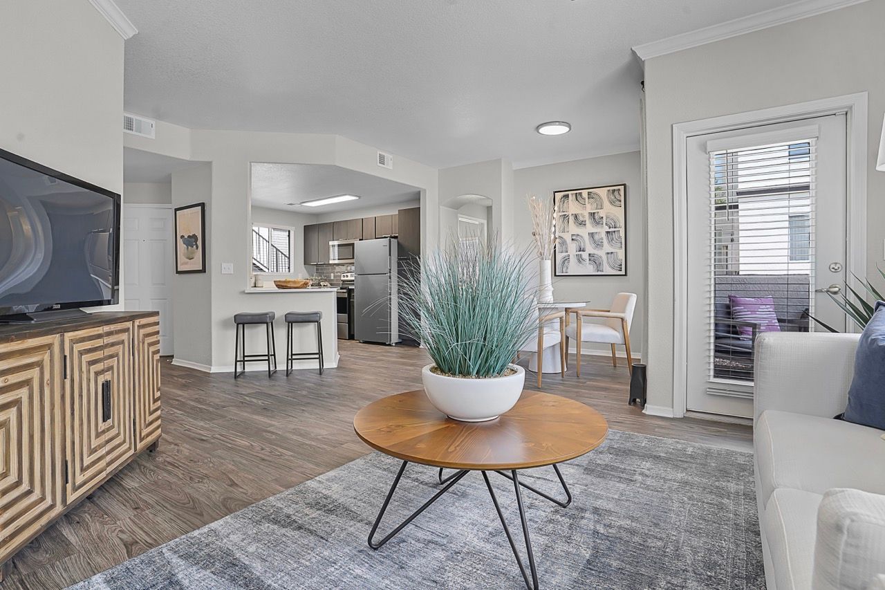 Open-concept living room with sofa, round wooden coffee table, and kitchen visible at Broadstone Heights in Albuquerque, NM.
