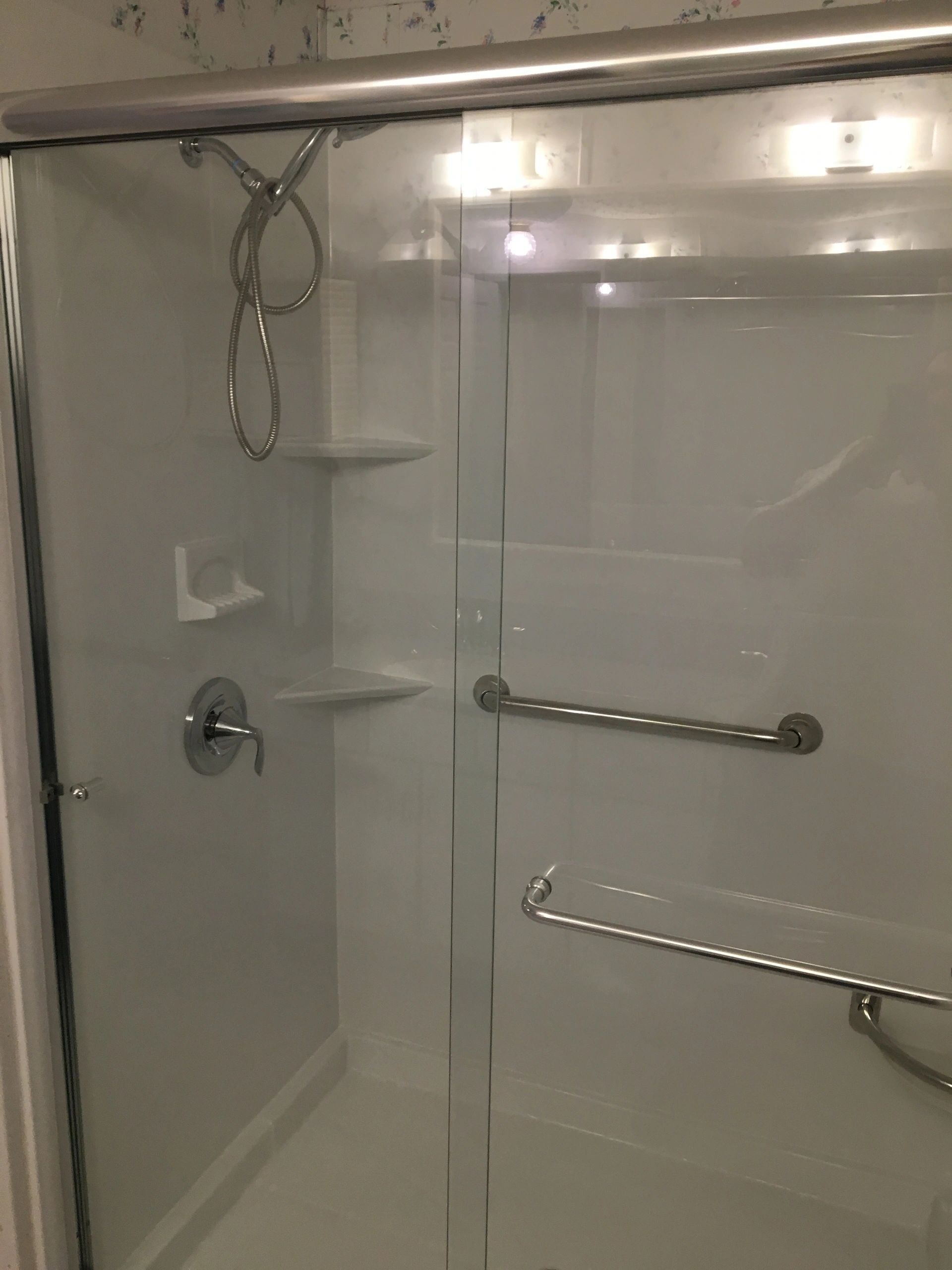 A shower with a sliding glass door and a shower head.