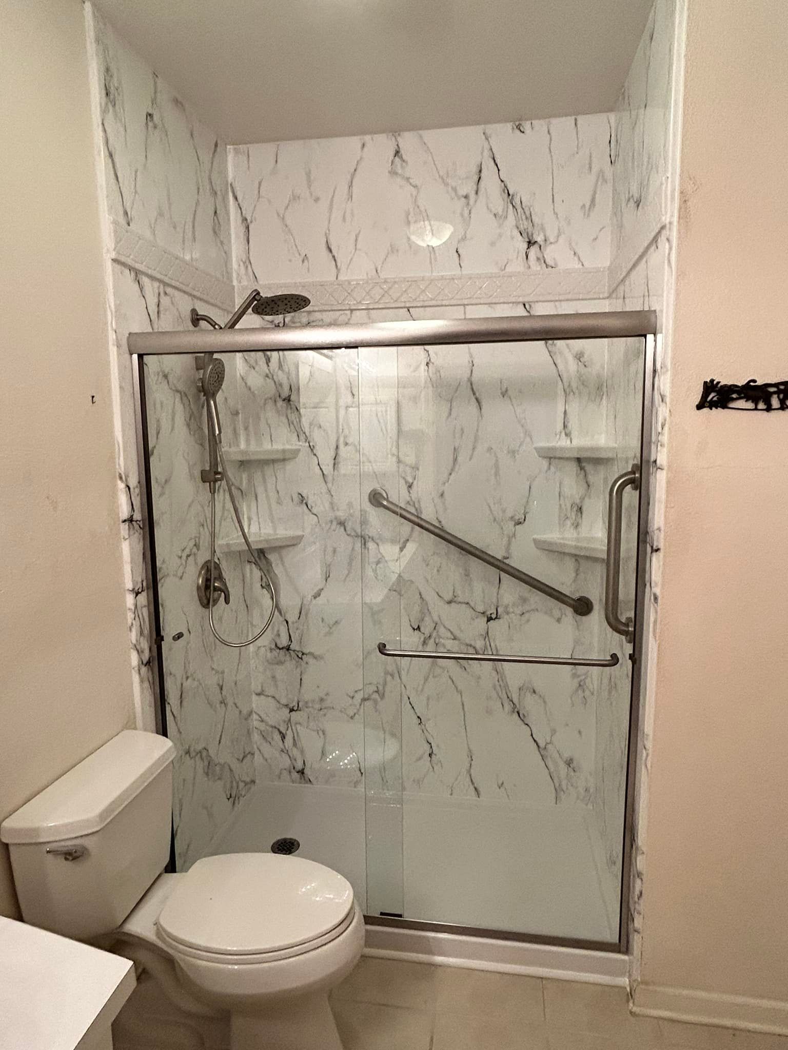 A bathroom with a toilet , shower , and marble walls.