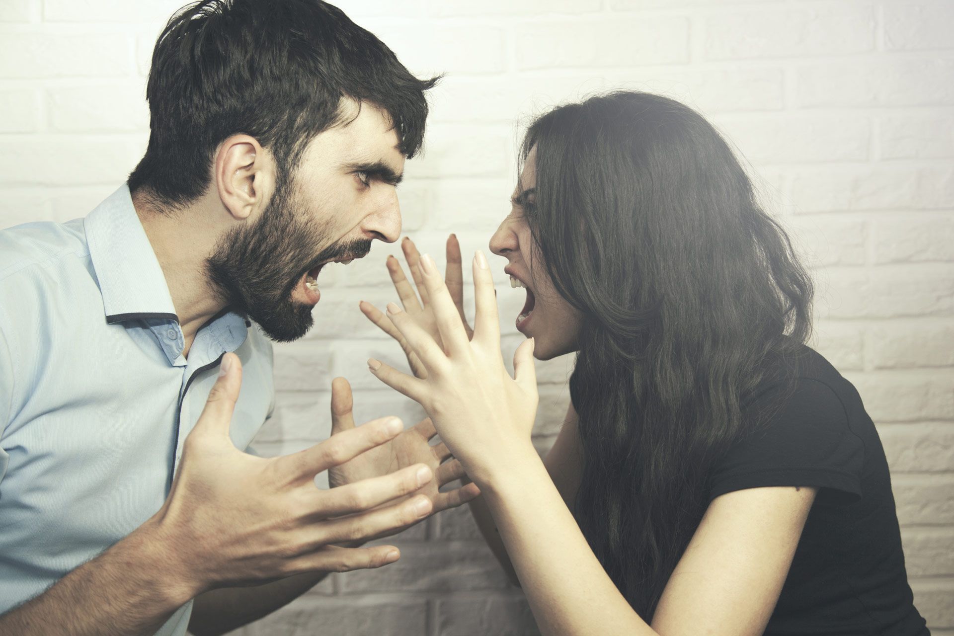 Man and woman yelling at each other, hands up, angry expressions.