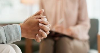 Couple on blue couch in therapy session, facing a therapist.