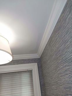 White ceiling with crown molding, gray textured wallpaper, and a window with blinds.