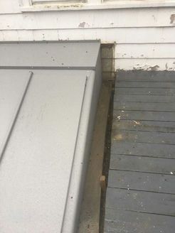 Gray ramp next to a weathered, gray deck. The siding on the building is white.