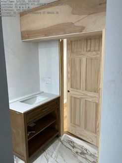Bathroom with wooden vanity, open door, and marble-like floor.