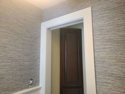 Doorway with white trim and gray textured wallpaper.