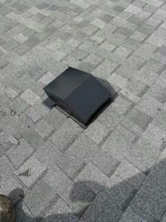 Black roof vent on gray asphalt shingles.