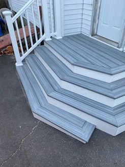 Gray composite stairs with white trim and railing leading to a white door.