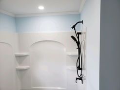White shower stall with black shower fixtures against light blue and white walls.