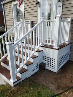 White railing and stairs leading to the front door of a house with light beige siding.