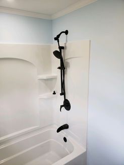 White bathtub with black shower fixture against light blue wall.