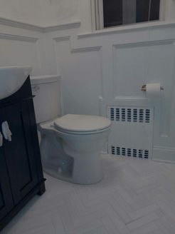 White bathroom with a toilet, cabinet, and radiator.