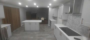 Modern kitchen with white cabinets, island, and wood-paneled wall.