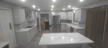 Modern kitchen with white cabinets, stainless steel appliances, and a marble island.