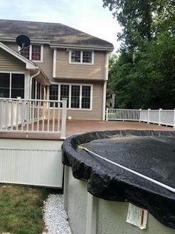 Backyard with a deck, pool, and house. Tan house with white trim. The pool is covered in black material.