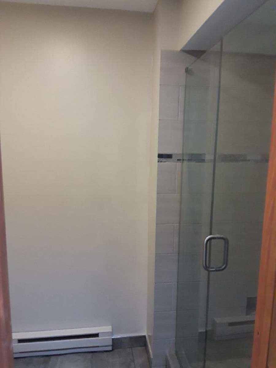 Bathroom interior with a glass shower enclosure and a wall-mounted heater.