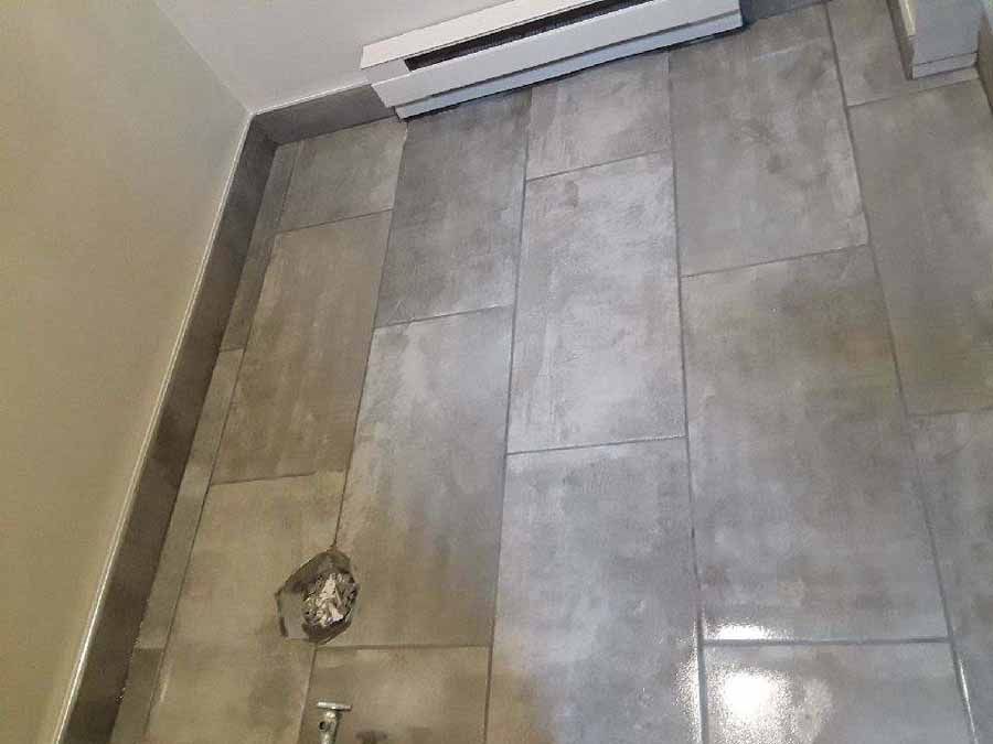 Gray tiled shower wall with a heater and showerhead.