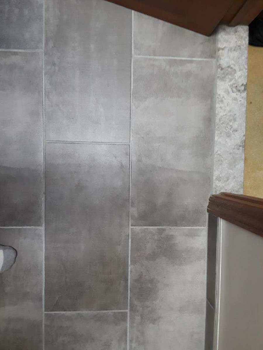 Gray rectangular tiles on a floor, with a brown edge on top and the side.