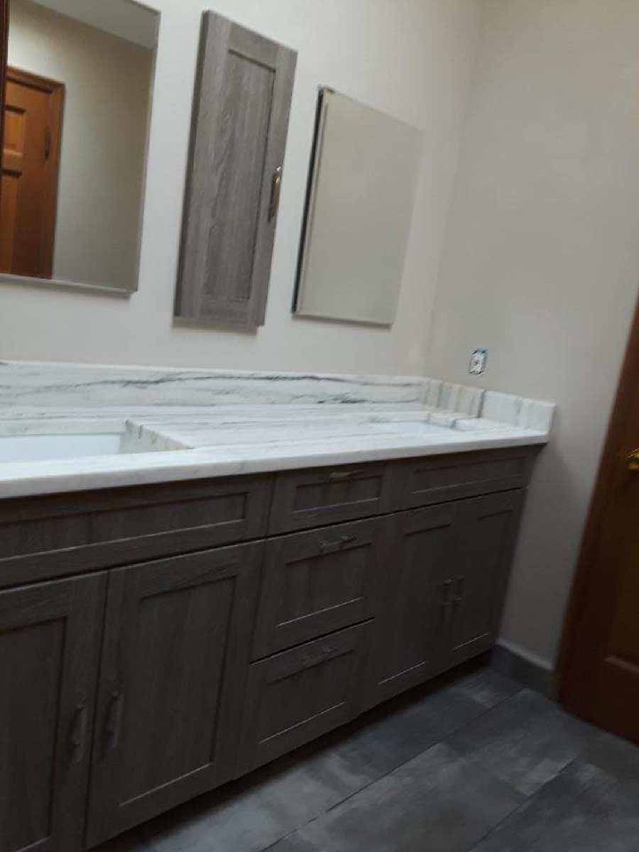 Bathroom with gray cabinets, white countertop, mirrors, and wood-look flooring.