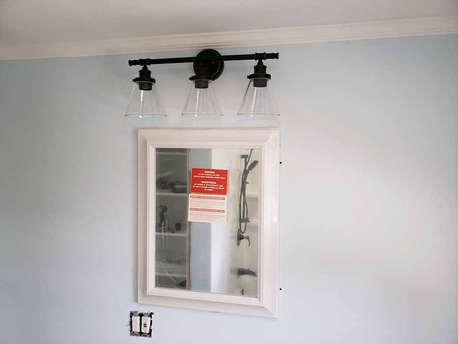 Bathroom with mirror, light fixture, and light blue walls.